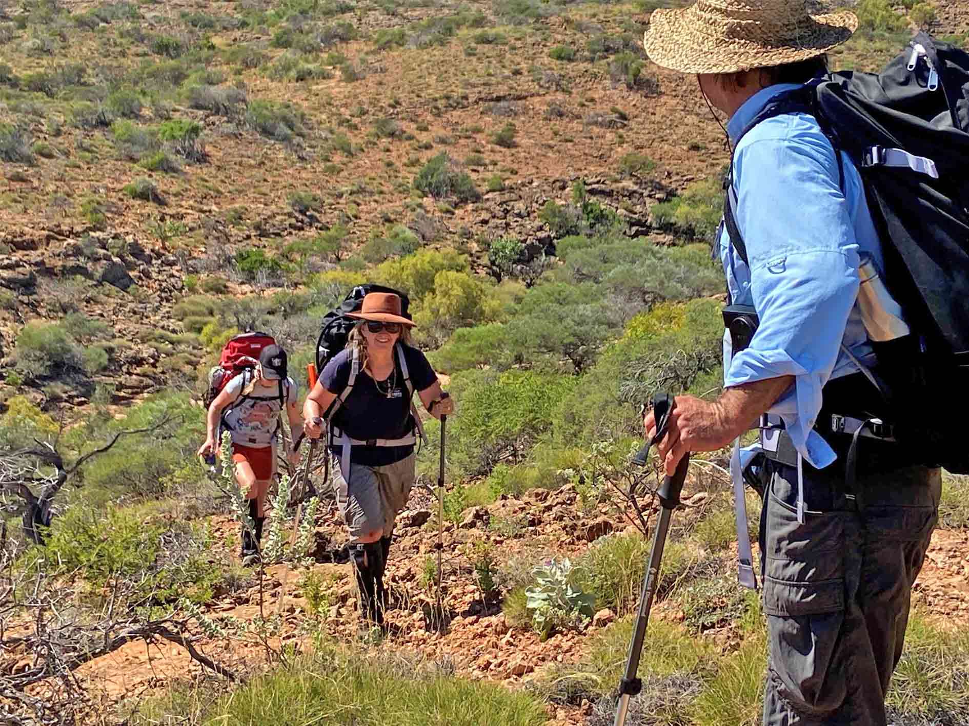 2 people hiking up a rocky gully amongst the arid shrublands of Cape Range